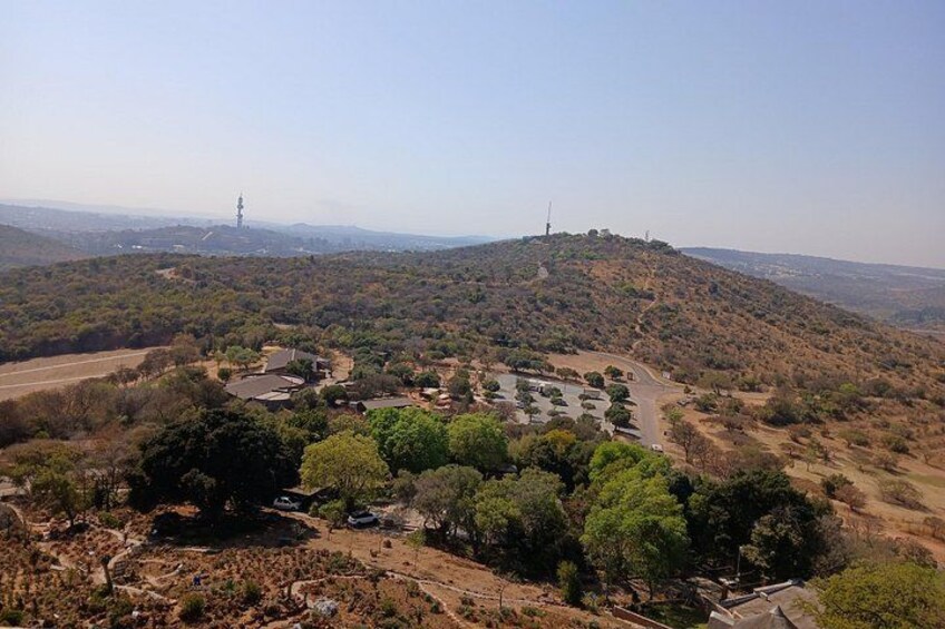 A hilly landscape with scattered trees, a road, and a distant tower. 5