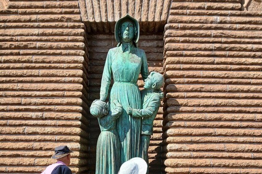 A statue of a woman holding a child, set against a stone wall. 4