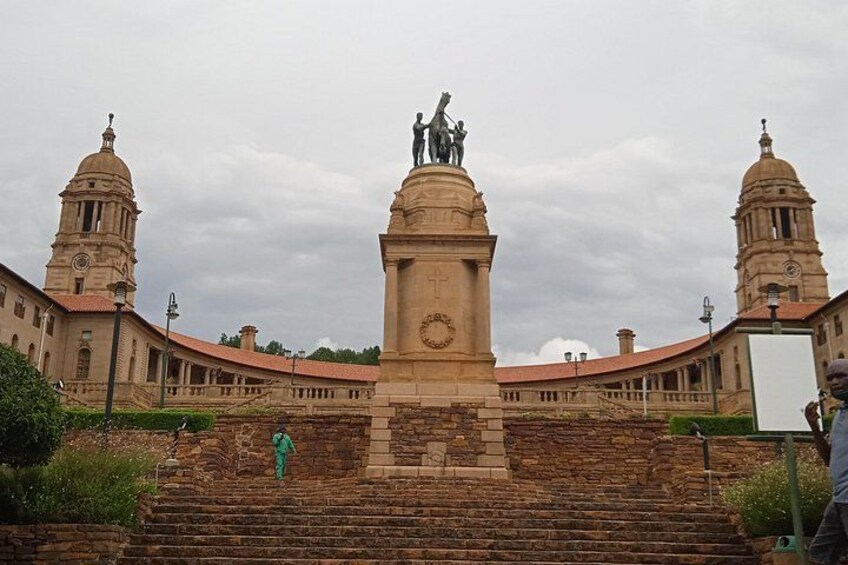 A historical building with a central monument, two domed towers, and a clock tower. 1
