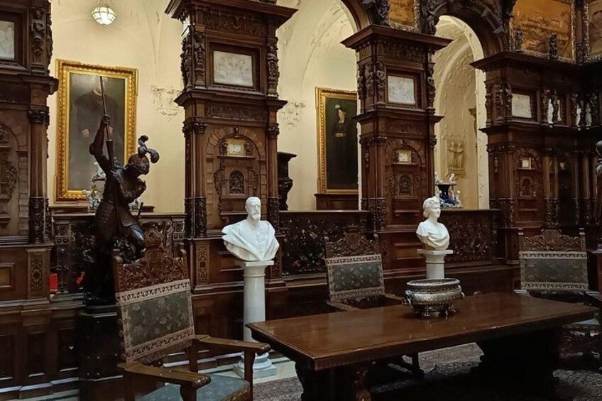 An ornate room with wooden furniture, a large table, and bust sculptures. 3