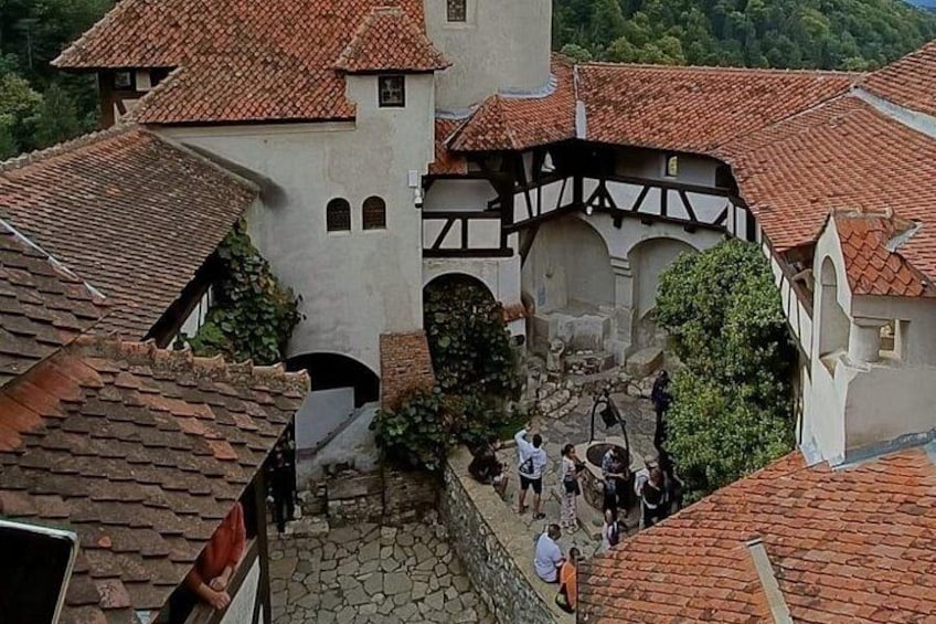 Une ville médiévale aux toits couverts de tuiles rouges, avec une église et des passants qui déambulent dans la rue pavée. 4