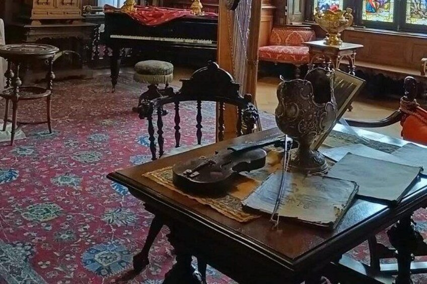 A room with a piano, a table with a book, a decorative vase, and a patterned carpet. 2