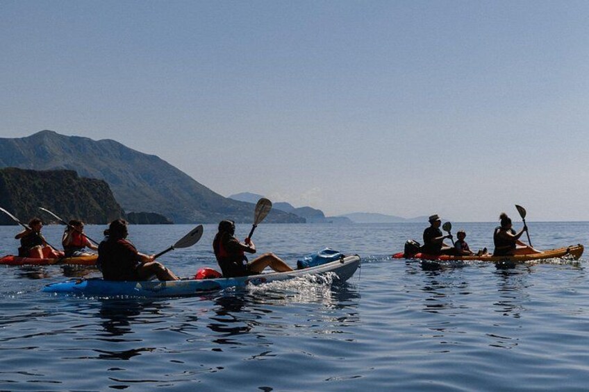People kayaking on a calm body of water with mountains in the background. 5