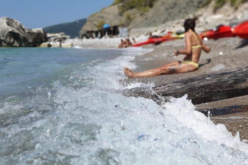 Budva Kayak & SUP Rental – woman sunbathing on a rocky beach beside red kayaks at Calipso Beach, Montenegro 4