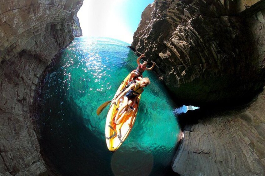 A kayak navigating through a narrow water channel between rocky cliffs. 4