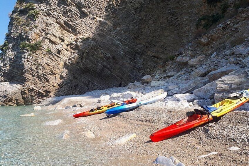 Budva Kayak & SUP Rental – colorful kayaks lined up on a pebble beach flanked by cliffs at wild beach of Sveti Nikola island, Montenegro 3