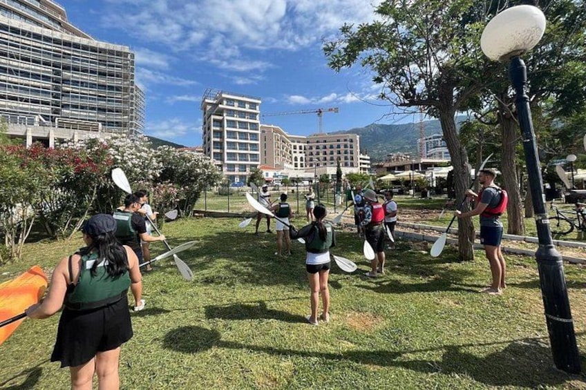 People kayaking in a grassy area with buildings in the background. 3
