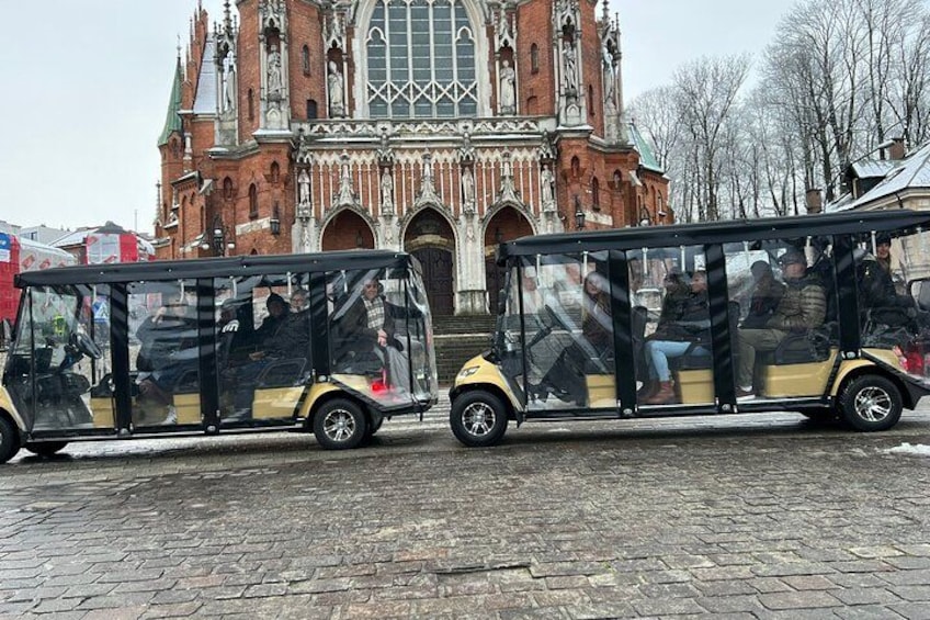 Two open-top buses parked in front of a historic church with intricate architecture. 5