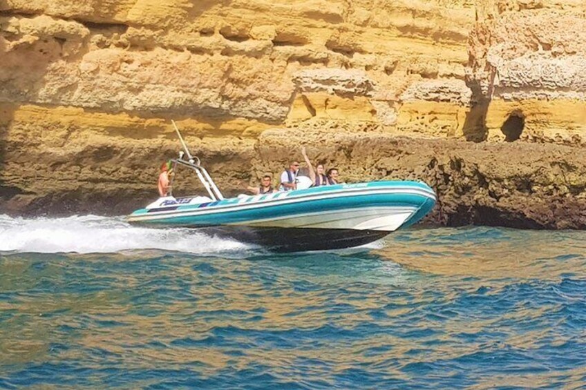 A speedboat with passengers navigating near a rocky coastline. 4