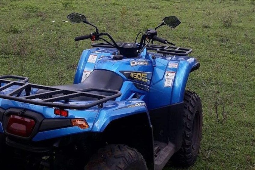 A blue ATV with a license plate, parked on grass. 1