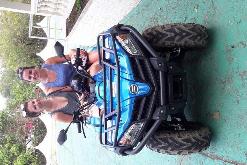 A blue ATV with large tires parked on a driveway. 2