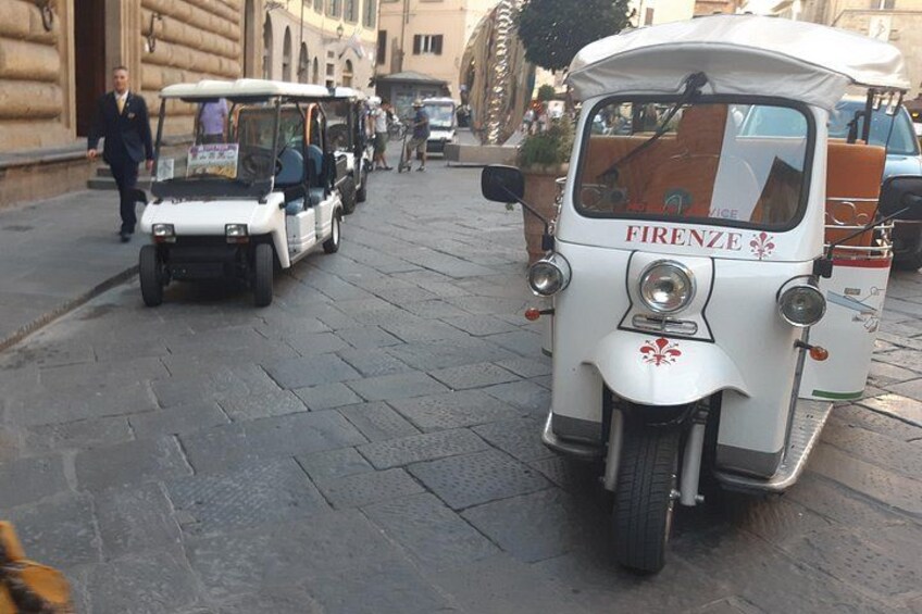 A vintage car with 'FIRENZE' written on it parked on a cobblestone street. 3