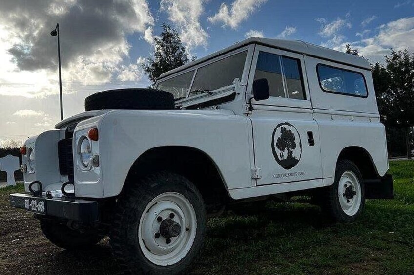 A white off-road vehicle parked on grass with a logo on the side. 2