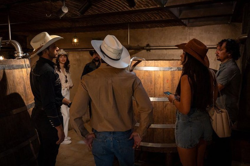 A group of people in a rustic interior with wooden barrels and a rustic ceiling. 2