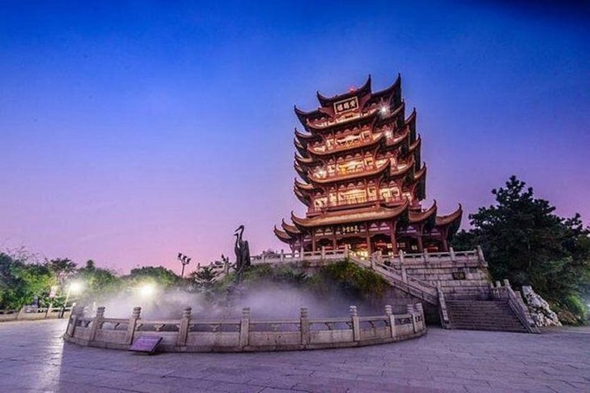 Una pagoda tradicional de varios niveles con luces iluminadas, rodeada por un sendero de piedra y una pequeña fuente. 1