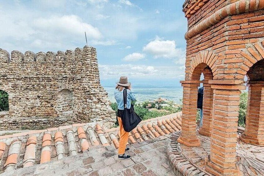 A person walking on a stone pathway, a brick structure, and a view of the sea. 3