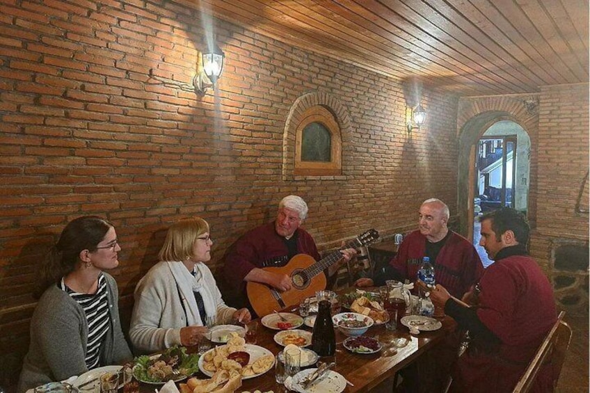 A group of people dining in a brick-walled room with a wooden ceiling and arched doorways. 5