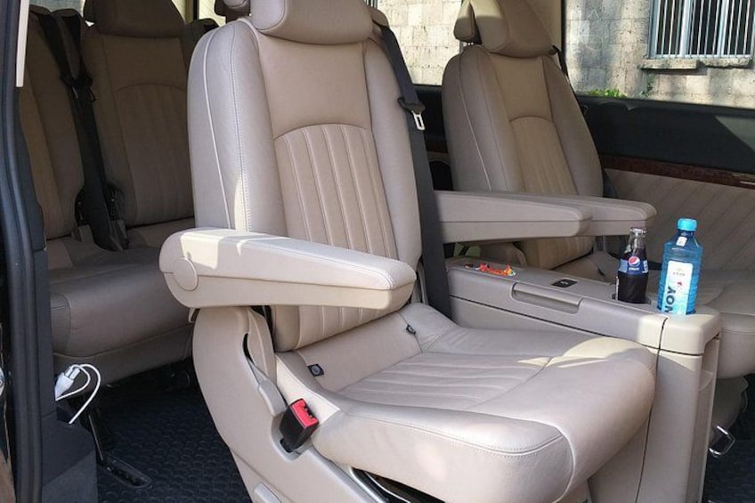 A car interior with beige leather seats, a cup holder, and a bottle of water. 2