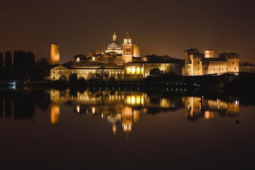 A historic building with a dome and towers, reflecting on a calm body of water at night. 5