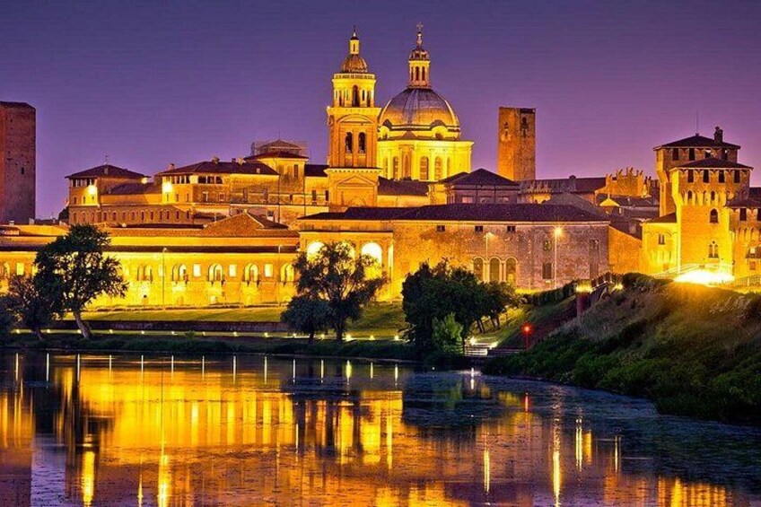 A historic building complex with a large dome and bell towers, reflecting on a calm body of water. 1
