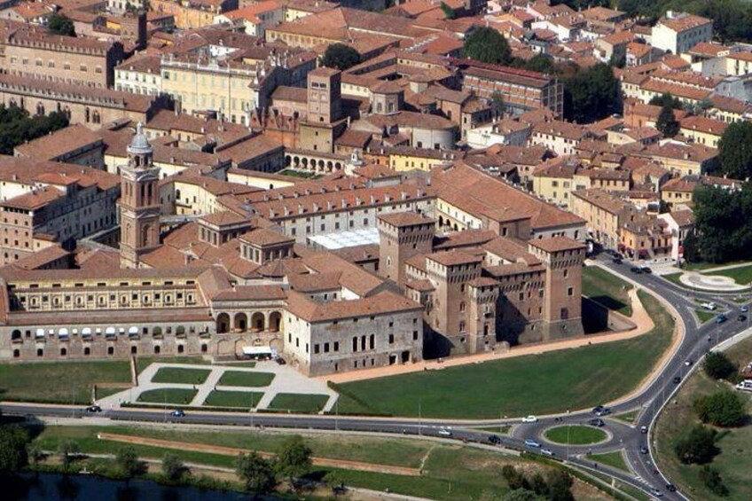 An aerial view of a historic city center with medieval architecture, a large open square, and a modern highway. 3