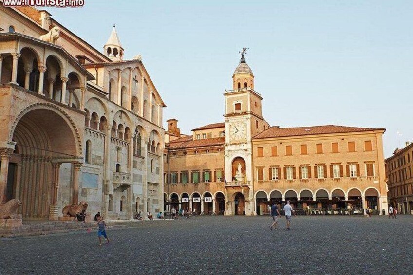 A historic square with a prominent clock tower, arches, and a cobblestone ground. 5