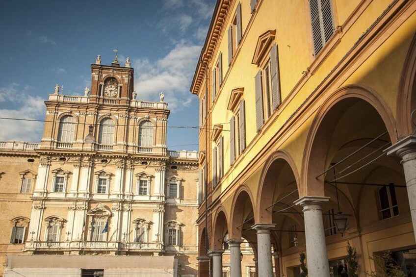 A historic building with a clock tower, arched walkways, and classical architecture. 1