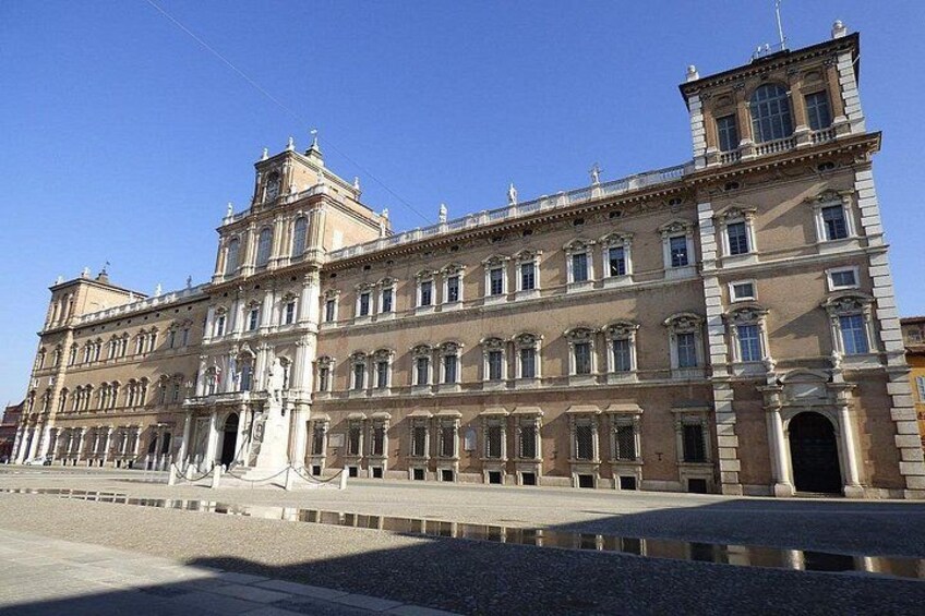 A large, historic building with classical architecture, featuring multiple stories, arched windows, and a prominent entrance. 3
