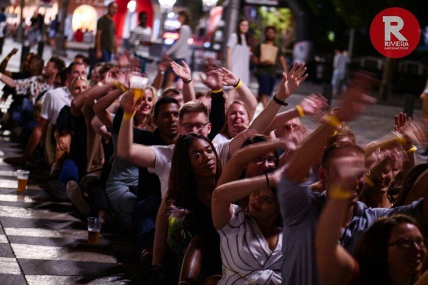Une foule de personnes assises par terre, dont certaines tiennent des boissons à la main. 5