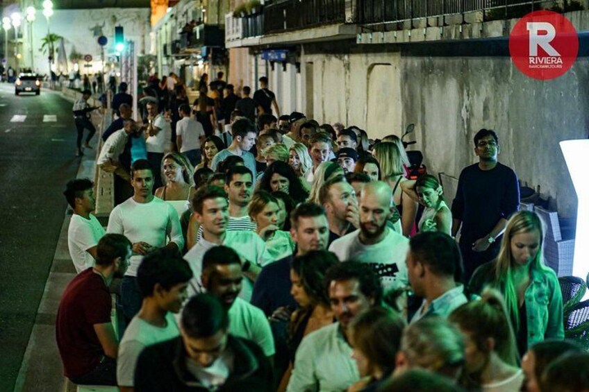 Une rue animée, de nuit, où l’on voit des gens qui marchent et qui sont debout. 4
