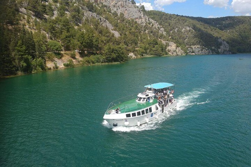 A boat on a turquoise lake surrounded by green hills. 3