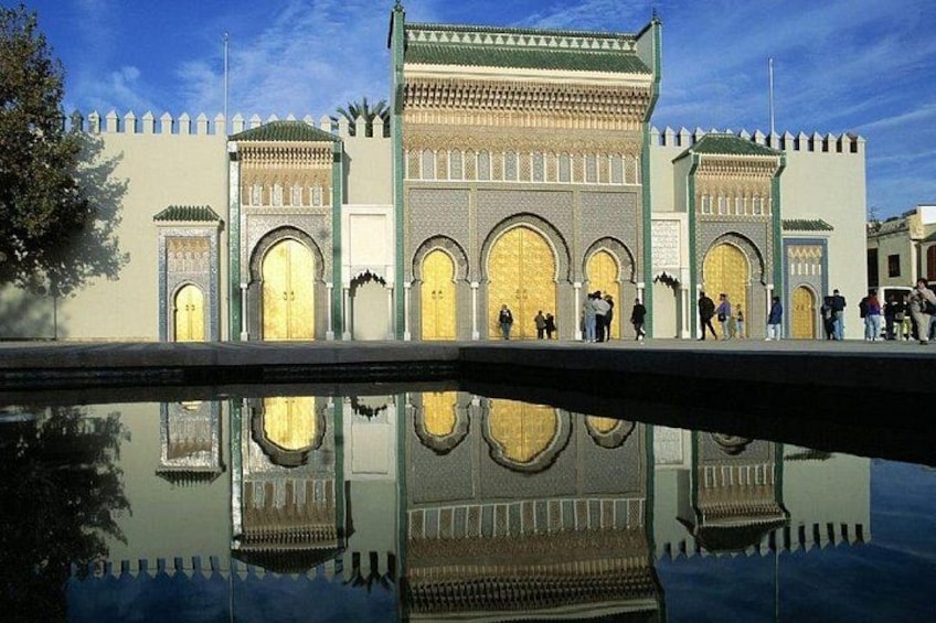 Un edificio histórico con amplias puertas arqueadas y detalles arquitectónicos intrincados, reflejados en una masa de agua frente a él. 2
