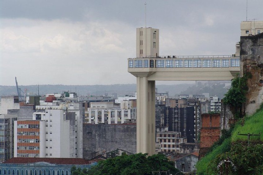 Un puente peatonal sobre un paisaje urbano con edificios y una colina. 2