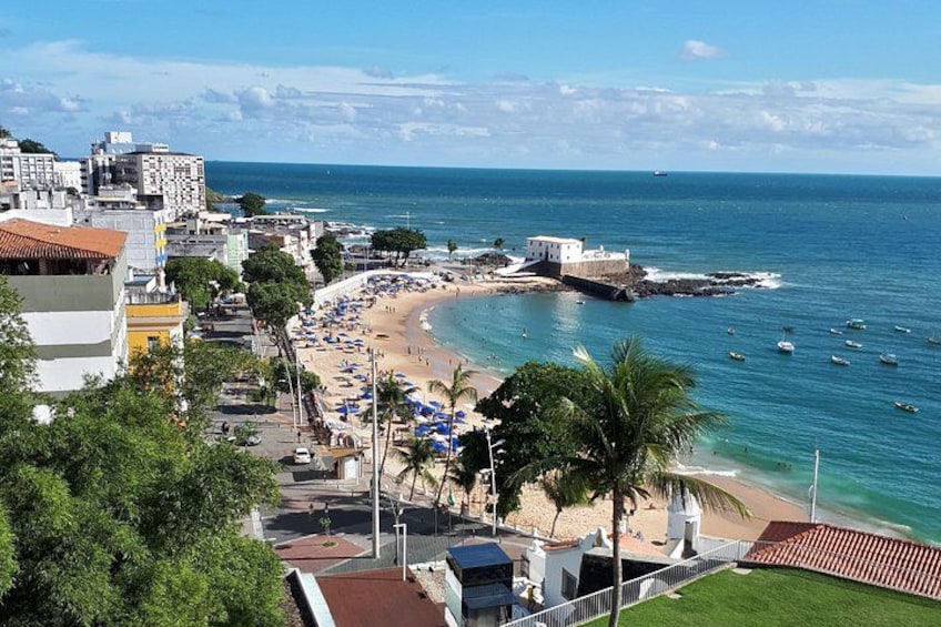 A coastal cityscape with a beach, boats, and buildings. 1