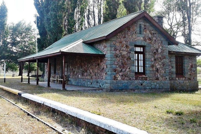 A stone building with a green roof, a bench, and a wooden fence. 2