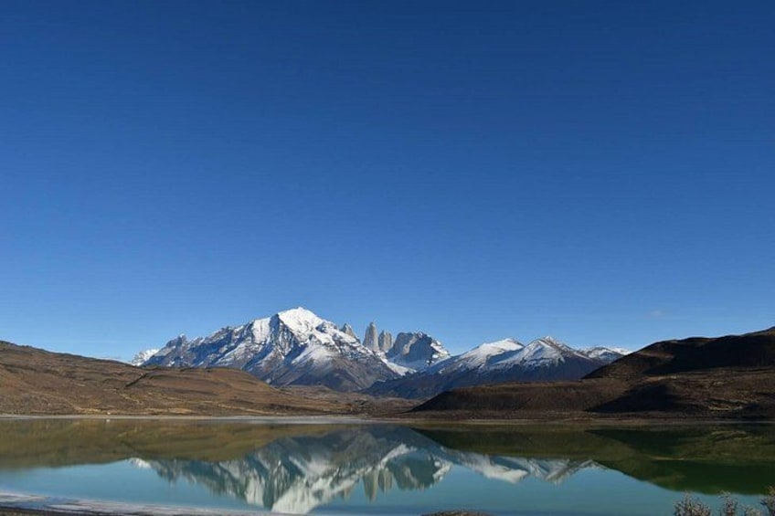 Een bergketen met besneeuwde toppen, een helderblauwe lucht en een spiegelglad meer. 5