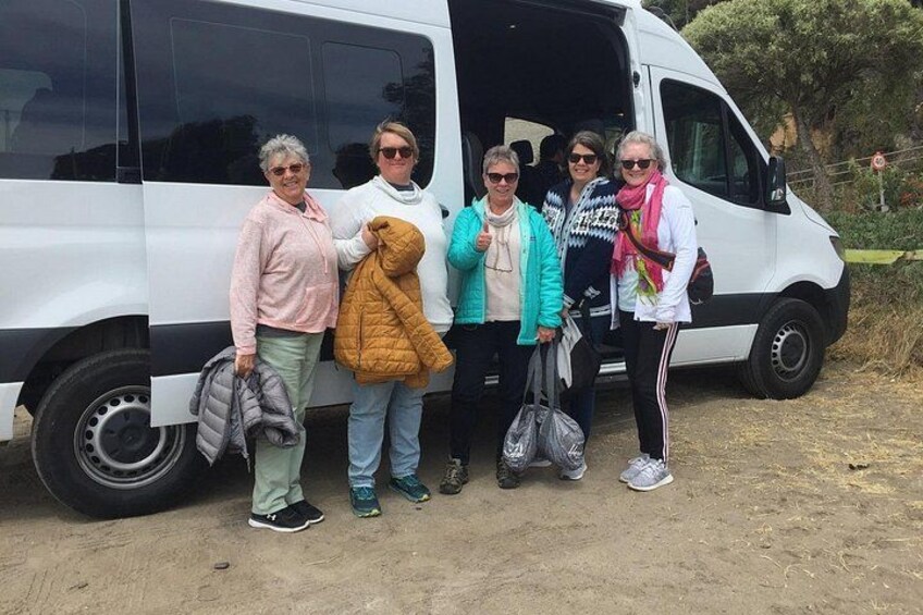 A group of people standing in front of a white van with its door open. 2