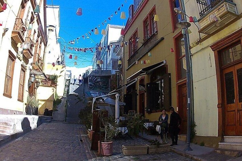 Una calle estrecha con edificios, una escalera y un cielo azul. 2