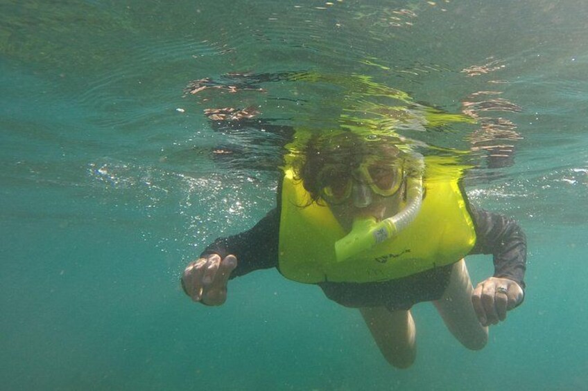 A person underwater wearing a yellow life jacket and snorkel. 3
