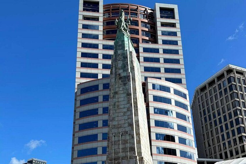 A tall building with a statue on top, surrounded by other high-rise buildings. 4