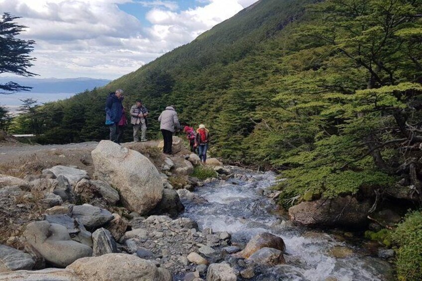 A group of hikers on a rocky trail with a flowing stream. 1