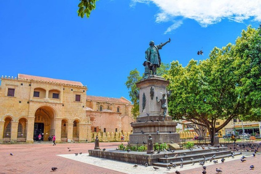 Una plaza con una estatua, un edificio histórico y palomas. 3