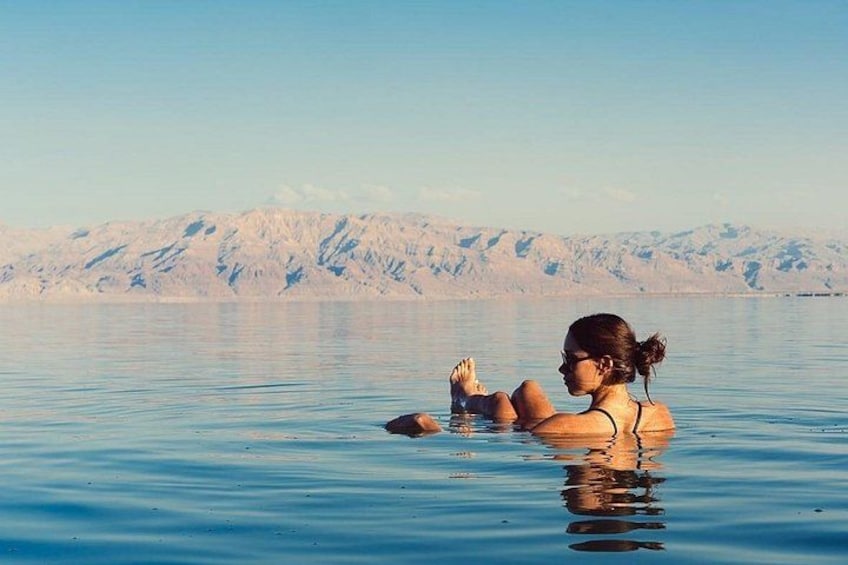 A person floating in a body of water with mountains in the background. 3
