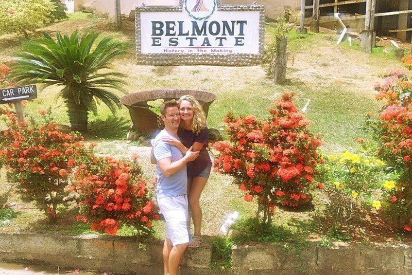 A couple embracing in front of a sign that reads 'BELMONT ESTATE History in the Making.' 1