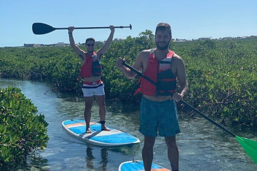 Two people paddleboarding on a river surrounded by mangroves. 3