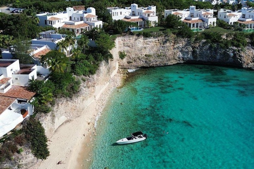 Un pueblo costero con edificios blancos, una playa de arena y un bote en aguas turquesas. 5
