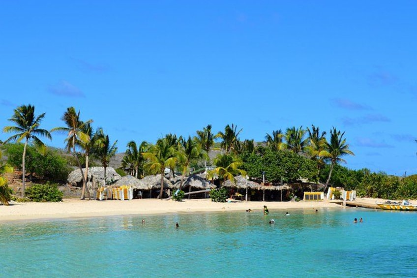 Una playa con aguas turquesas cristalinas, palmeras y cabañas con techo de paja. 3