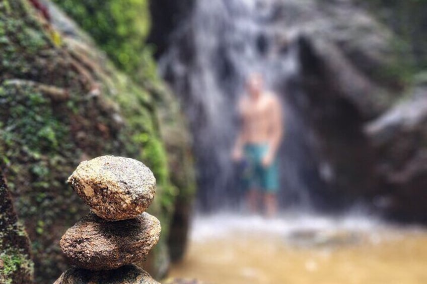 Una pila de rocas en un entorno natural con una cascada desenfocada al fondo. 2