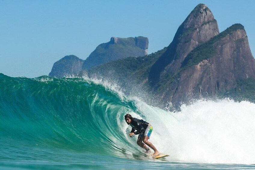 A surfer riding a large wave with mountains in the background. 1