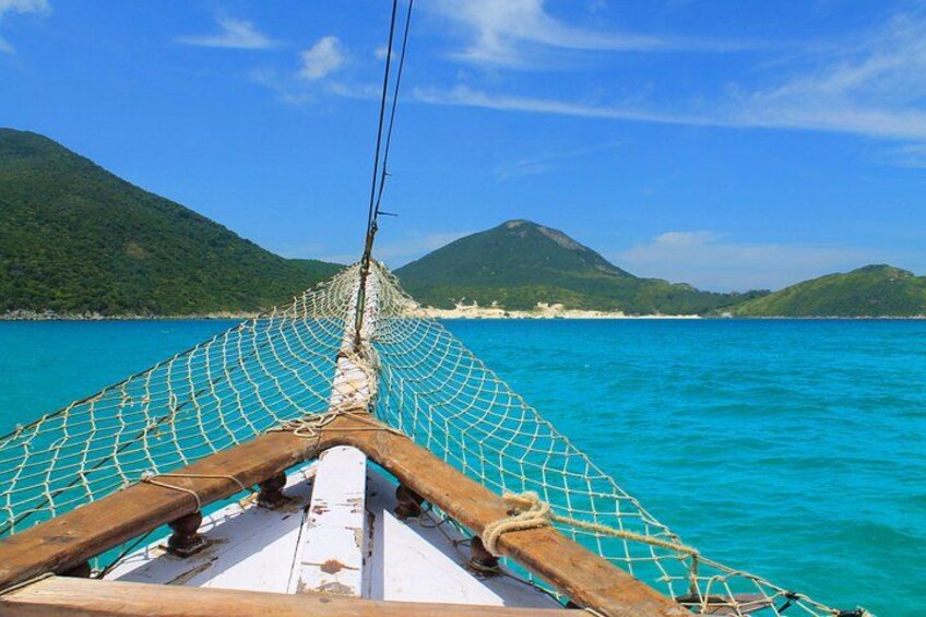 Ein Boot mit Netz und Holzstruktur, ruhiges türkisfarbenes Meer und grüne Hügel im Hintergrund. 1